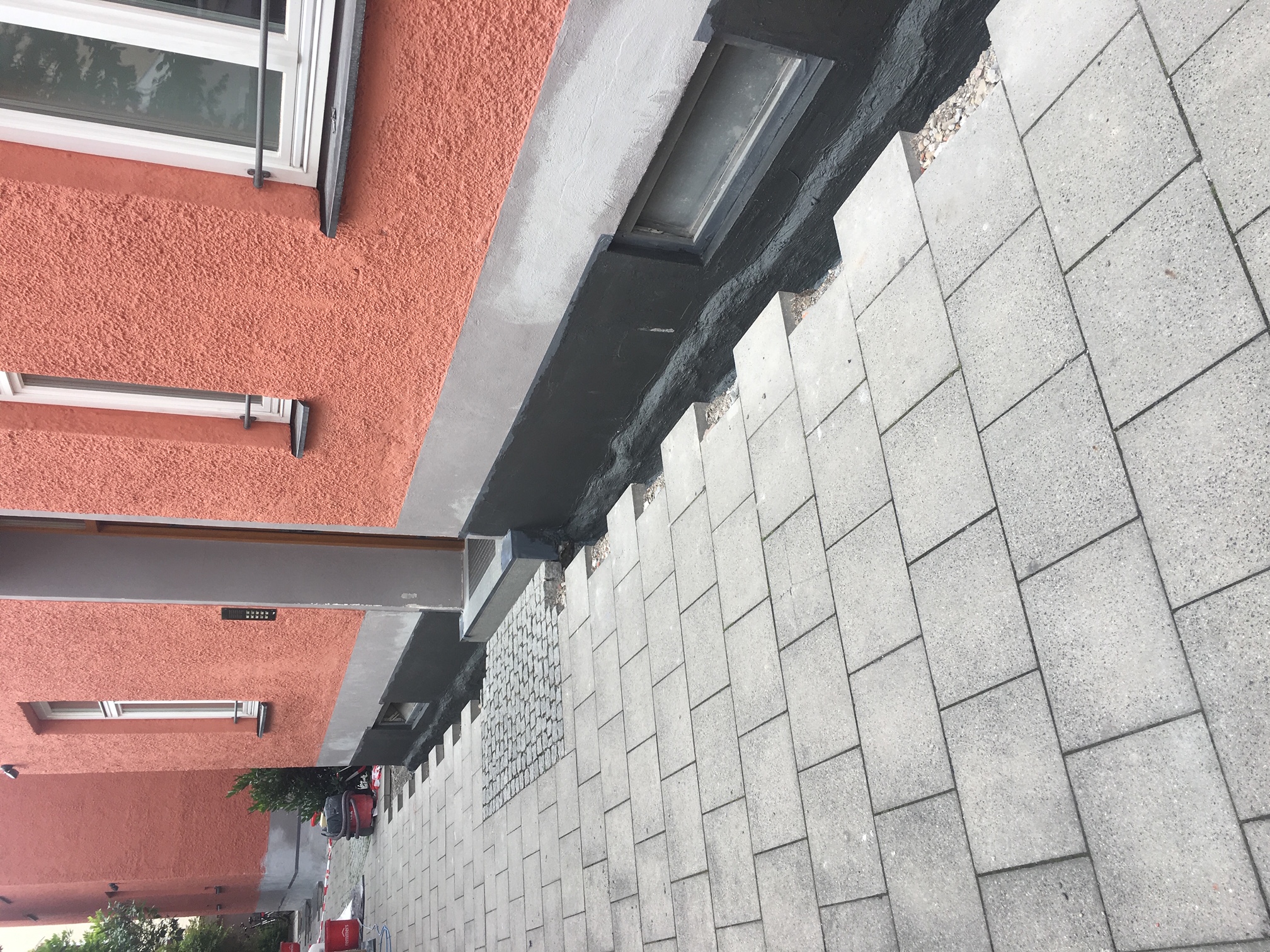 Sockelabdichtung mit anschließend neu verlegtem Pflaster.